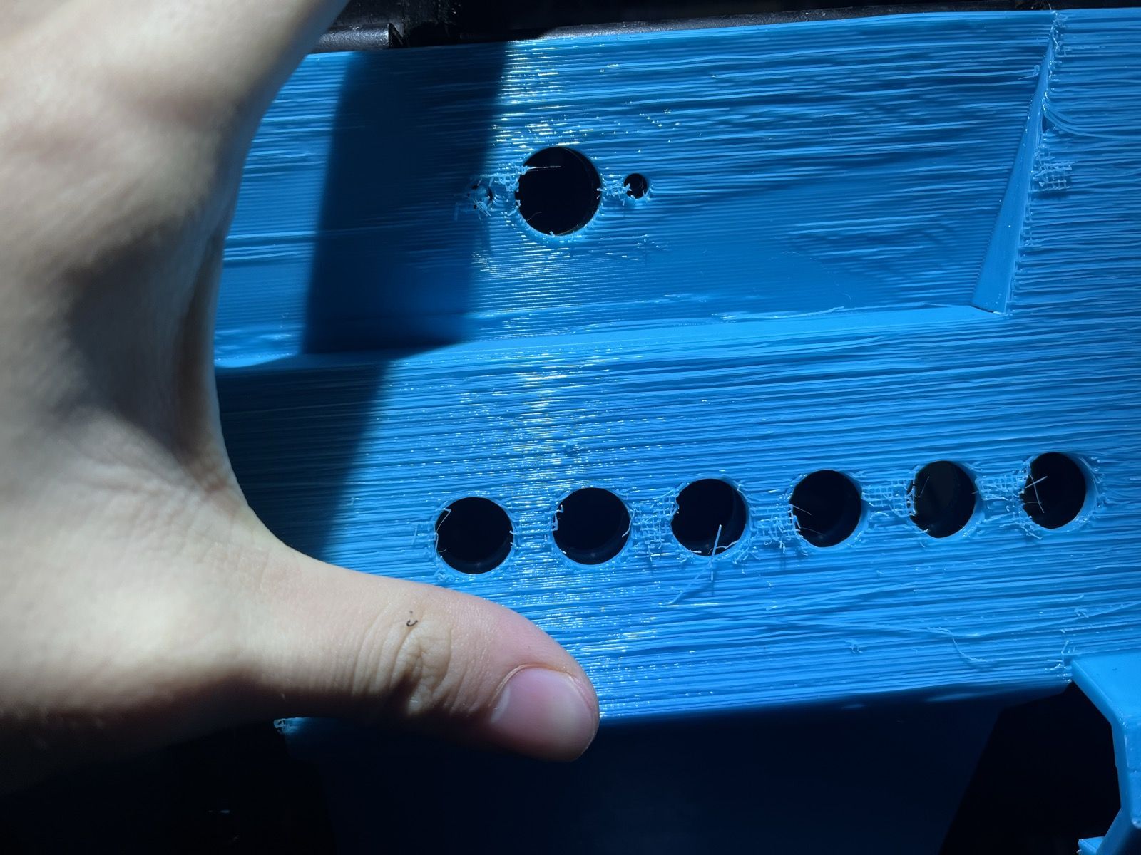 A blue 3D-printed prototype of part of the cockpit panel held in a hand